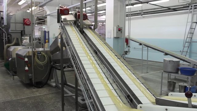 An infinitely long caramel billet moves on a conveyor belt in a confectionery factory.