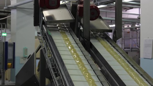 An infinitely long caramel billet moves on a conveyor belt in a confectionery factory.