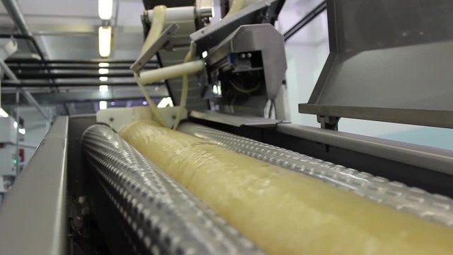 An infinitely long caramel billet is wound into one huge billet in automatic production at a confectionery factory.