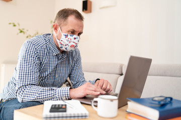 Portrait of pensive young businessman with surgical medical mask in shirt sitting, shocked looking at laptop display with stressed face. Home office and health care concept. World pandemic.