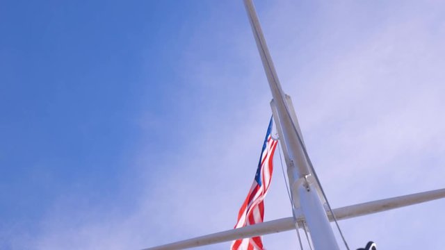 American Flag and Pole Blowing in the Wind with blue sky and white cloud background