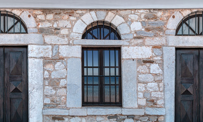 Fototapeta na wymiar Old architecture stone house with blue sea reflection on windows