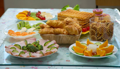 Croissants, waffles, fruit, vegetables, meat on breakfast table, healthy eating