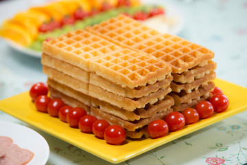 Waffles on yellow plate with cherry tomatoes, homemade healthy breakfast