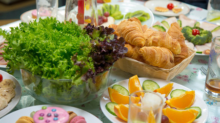 Organic lettuce, croissant, orange, cucumber on table, healthy breakfast concept