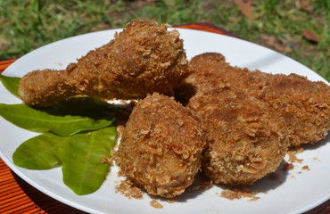Four crispy fried chicken legs on white plate, fried fast food