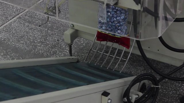 Packed in plastic bags, caramel candies are delivered from the packaging machine to the conveyor belt.