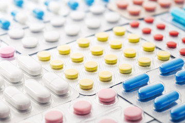 pile of medical pills  in red, blue and yellow colors in  silver plastic packaging