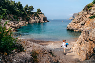 A young woman in a hat and with a waterproof bag and a blue, folding rug for tourism. It stands...