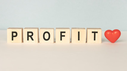 Profit text written on wooden block on dark grey background, business investment concept.
