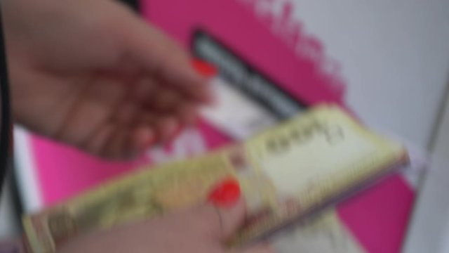 Female hands replenish the bank terminal with banknotes. Ukrainian money on the background of a bill acceptor of a banking terminal.