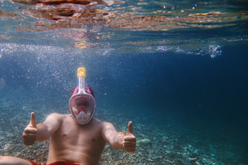 Snorkeler approves, likes, snorkeling man in full face mask, summer vacation activity, swimming in...