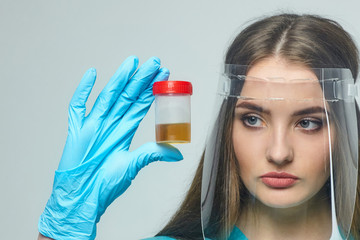 a female doctor holds a can of urine analysis in her hand