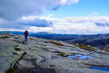 Tourist man on trail to Kjeragbolten. Amazing landscapes of the Norwegian mountains.