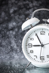 Obraz na płótnie Canvas white retro alarm clock in a black background under the water drops.. Morning. Break. Motivation. Business solutions. Success. Deadline.