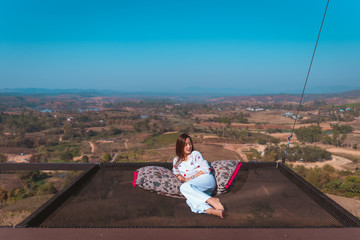 girl posing on The seat is made from a net that relaxes in touching the nature that overlooks the mountain in travel holiday relaxing concept