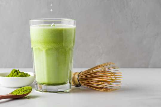 Matcha green tea iced latte with matcha powder and bamboo whisk