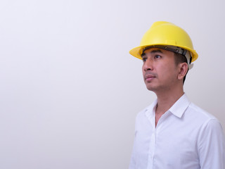 engineer with hands crossed wearing yellow helmet on white background