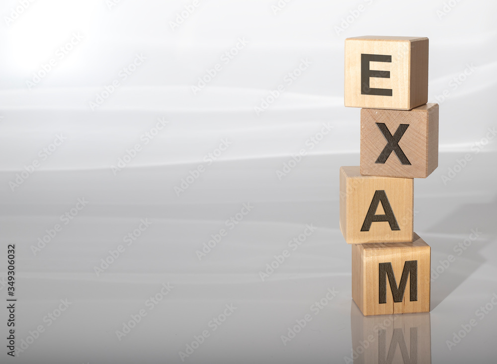 Poster concept word exam on cube blocks on a white grey glossy background with reflection. copy space avail