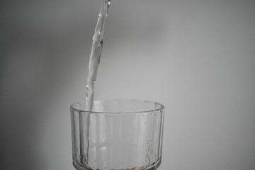 Transparent, pinkish gaseous liquid, falling into a crystal glass foaming