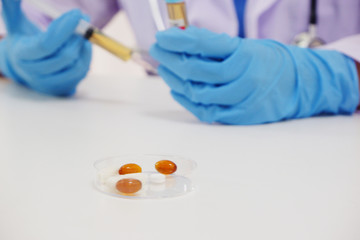 Close up of medicine and laboratory assistant's hands with syring on background