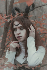 Fototapeta premium Gloomy girl with horns in the forest. Halloween image