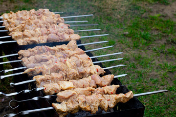 Cooking pork meat skewers, raw meat, fried product on fire, on the grill in nature in little village