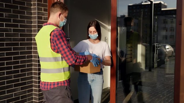 American courier delivers a cardboard box. An American young woman takes a parcel home. Credit card payment