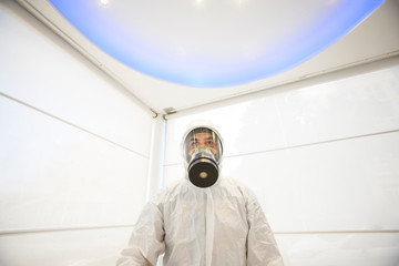 tecnico con respiratore protettivo e tuta bianca pronto per la sanificazione antivirus e antibatterica  in un locale .