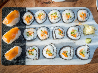 sushi on a plate/chopping board with ginger and wasabi