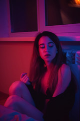 Portrait of a beautiful girl in blue and red light. Fashion portrait in the room