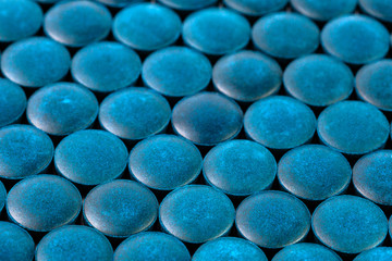 close-up background of many blue organic spirulina tablets laid tight in one layer on flat surface
