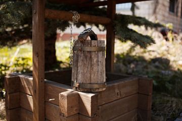 rustic well with a bucket and a chain of wood