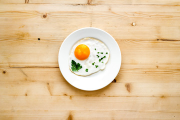 Fried eggs on plate - light wooden kitchen table top-down