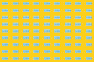 COVID-19 pattern of surgical face masks on yellow background. Protection against coronavirus. Healthcare and medical concept with copy space