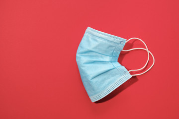COVID-19 disposable surgical face mask on red background. Protection against coronavirus. Healthcare and medical concept with copy space