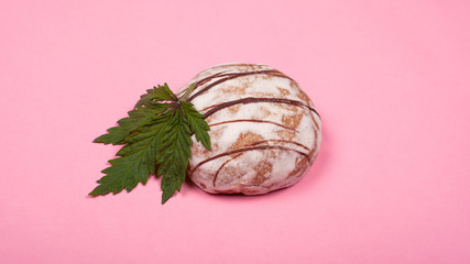 round sweet cookie with a leaf of marijuana on a pink background close-up, cannabis sweets, bakery products with marijuana
