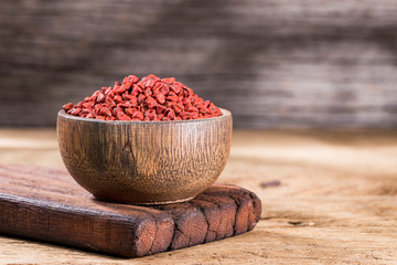 annatto seeds in bowl on wooden background