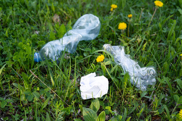 trash plastic bottles on the grass, plastic and paper and other garbage on the lawn