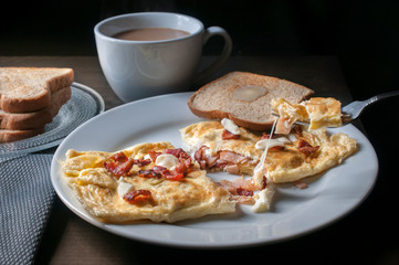 Bacon ham and cheese omelet with toast and coffee  on the side in a black background, morning food or breakfast concept