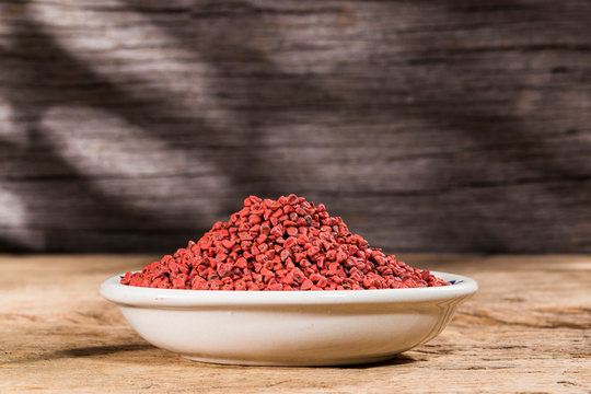 annatto seeds in bowl on wooden background