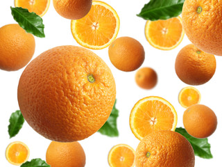 Levitation of a whole orange and slices with green leaves on a light background. Image with selective focus.