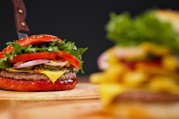 A set of different burgers. Fast food restaurant board. A diverse snack menu. Serving on a wooden board on a black background.