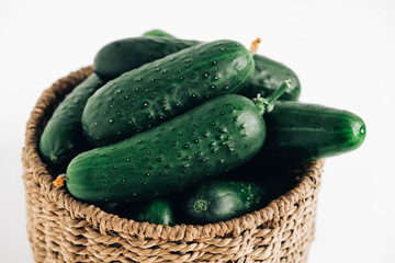 Cucumbers in a wicker basket on a white table background. Copy, empty space for text