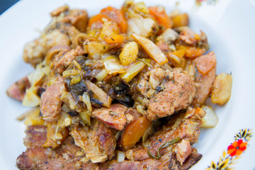 Traditional one pot dish of meat and vegetable done in a cast iron cauldron over a bonfire - a portion on a plate