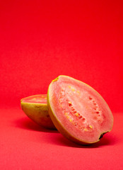 Pink guava cut in half on a pink background.