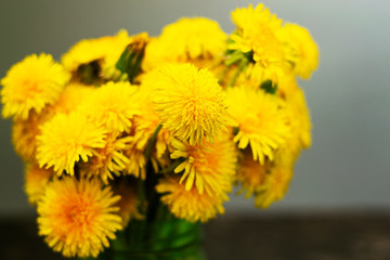 Bouquet of yellow flowers in a glass green jar.