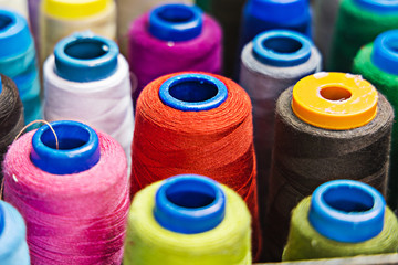 A pile of sewing reels with threads of different colors. Closeup. Side view. Background