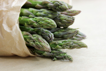 Green asparagus spears close-up. A bunch of fresh raw green asparagus on brown paper background. Concept to organic vegetables.
