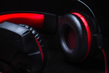 black-red headphones lie on a black background.
